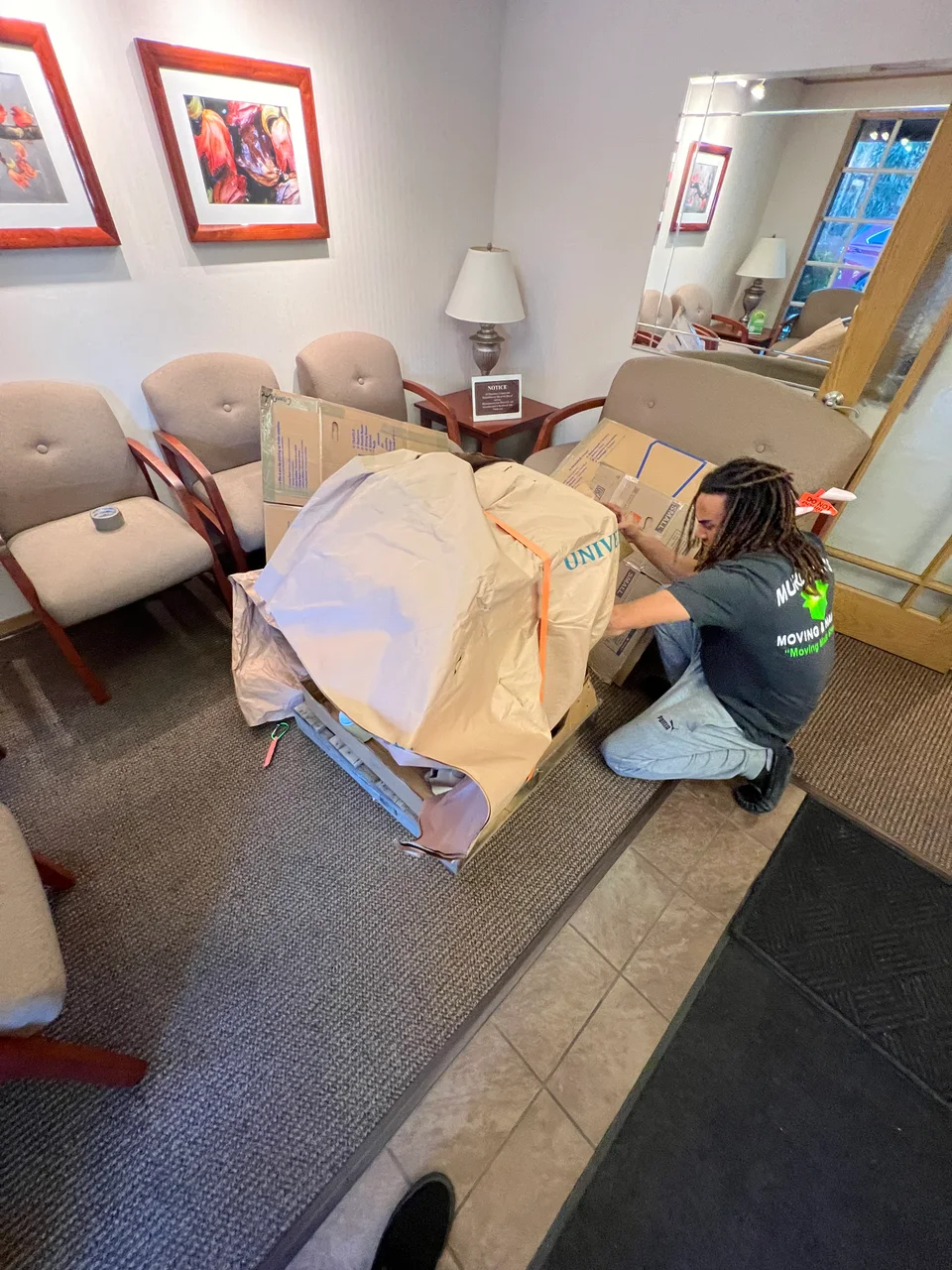 Murdock's Moving & Storage mover wraps furniture in protective paper amid boxes in a dining room