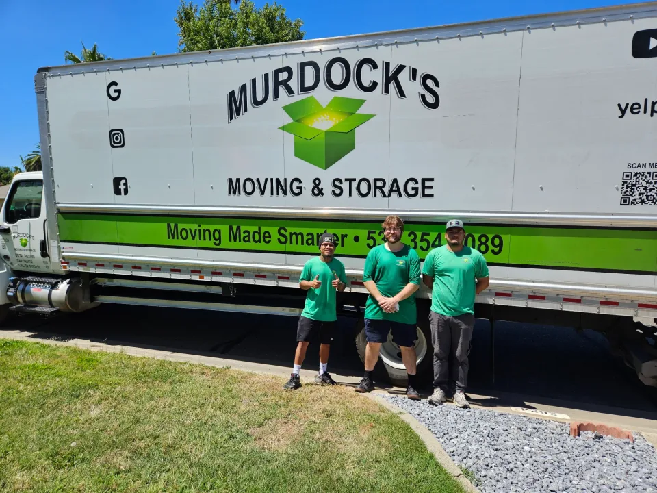 Three Murdock's Moving & Storage crew members standing in front of the branded Sprinter cargo van