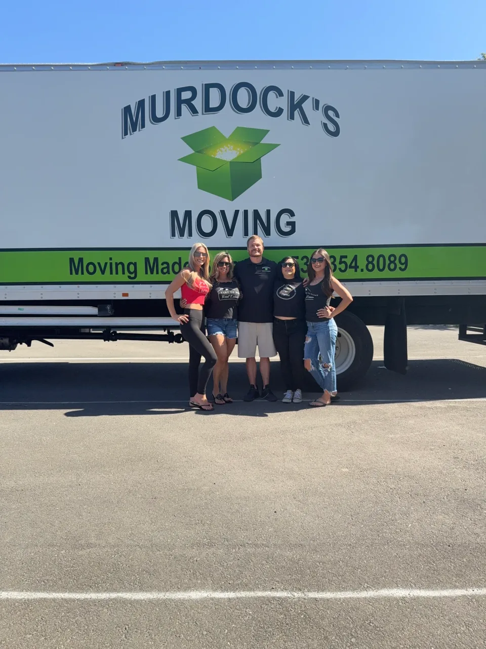 Murdock's Moving team member posing with four smiling clients in front of the branded moving truck
